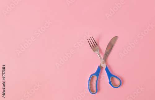 Creative view of scissors with fork and knife on pink background. Minimal design surreal concept. Copy space. Top view.