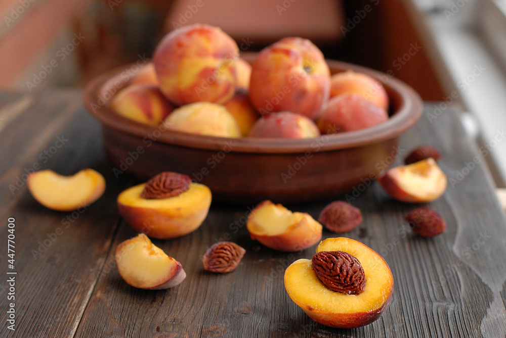 A round plate filled with ripe peaches and some cut peaches on a kitchen table. Cooking a fresh, healthy breakfast.