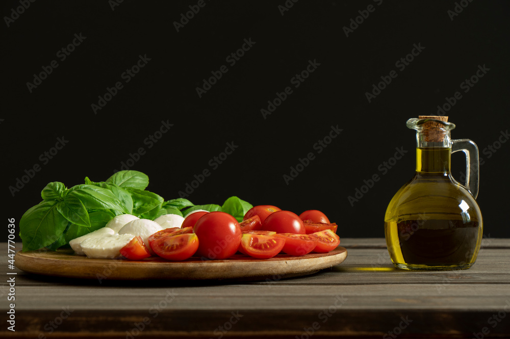 Olive oil bottle on black background with copy space. Mediterranean food. Dressing fresh vegetables salad. Olive oil bottle on black background with copy space. Mediterranean food. Dressing fresh vegetables salad.