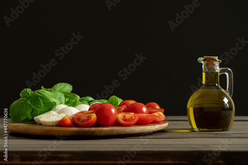Olive oil bottle on black background with copy space. Mediterranean food. Dressing fresh vegetables salad.
