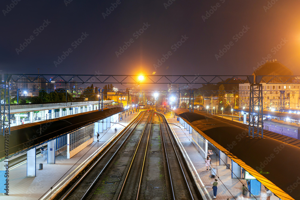 Fototapeta premium City train station at night with blurred people on the platform