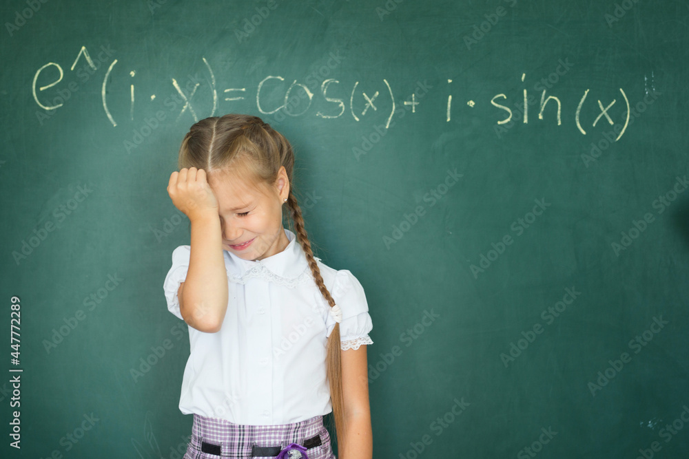 Child girl schoolgirl and compound formula on the chalkboard. Complex school program does not match the age of the child