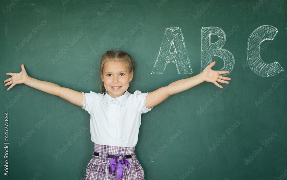 Portrait of caucasian happy child girl with. School chalkboard or blackboard background. Education concept