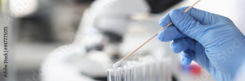 Scientist chemist inserting cotton swab into glass test tube closeup