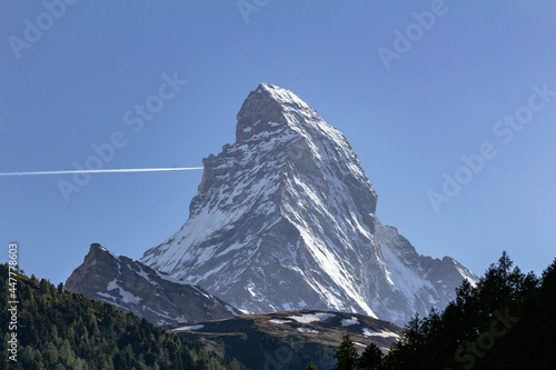 View of iconic Matterhorn mountain summit with snow from Zermatt valley, with green vegetation, trees and wooden cottages, Valais, Swiss Alps, Switzerland © Miguel
