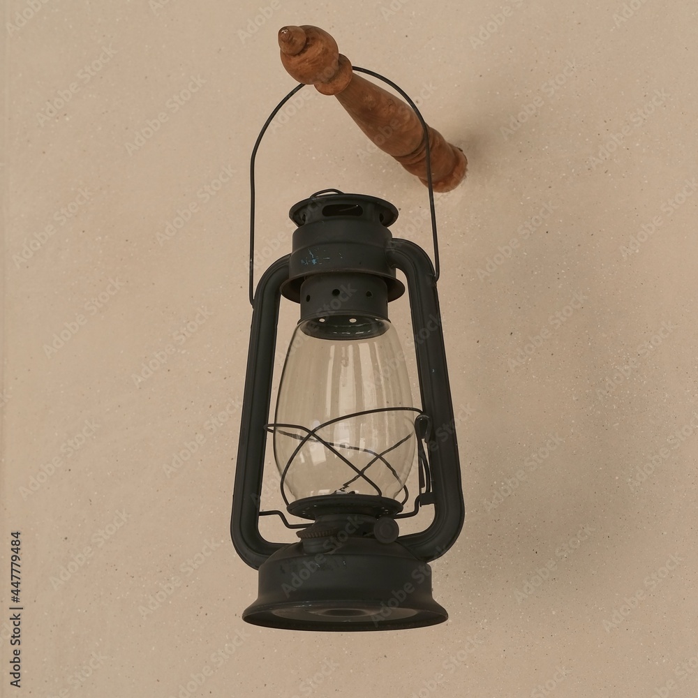 Vintage black gasoline lantern hanging on stucco wall background after