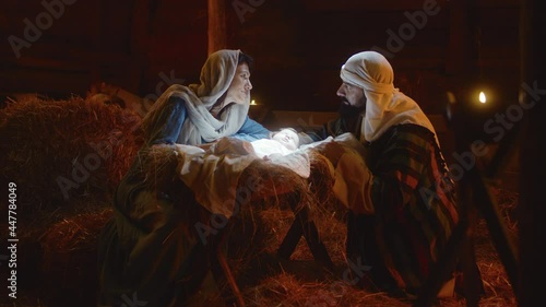 Mary and Joseph caressing baby Jesus in illuminated manger nativity scene photo