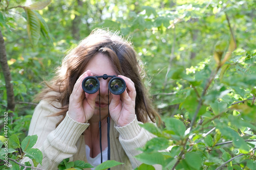 Obraz na plátně cunning curious European adult woman close-up, holding black field binoculars wi