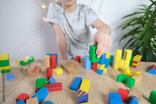 child, kid plays with colored wooden cubes, builds houses and rockets, concept of development of fine motor skills, tactile sensations, creativity, children's entertainment
