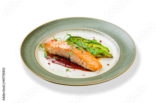 Salmon steak on the grill with avocado on plate isolated on white