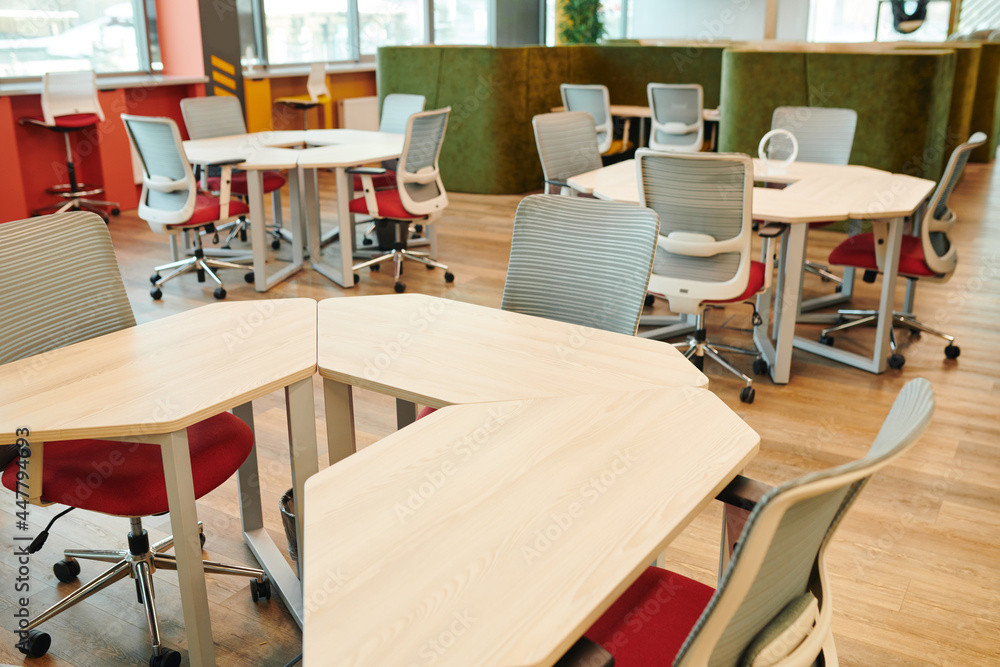 Interior of contemporary large open space office with many chairs by tables Interior of contemporary large open space office with many chairs by tables