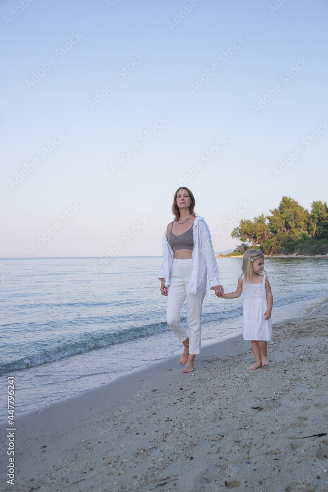 Mother and daughter walking on the beach. Family summer vacation concept.