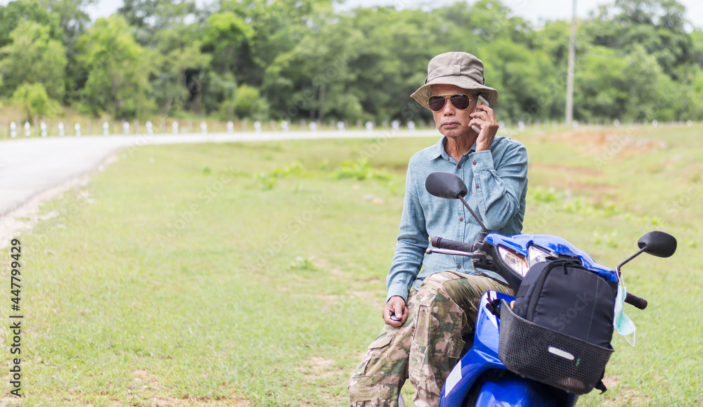 Senior man traveler with a motorbike in the countryside, using smartphone Senior man traveler with a motorbike in the countryside, using smartphone