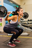 Young hispanic latina woman doing legs with a barbell as a gym workout