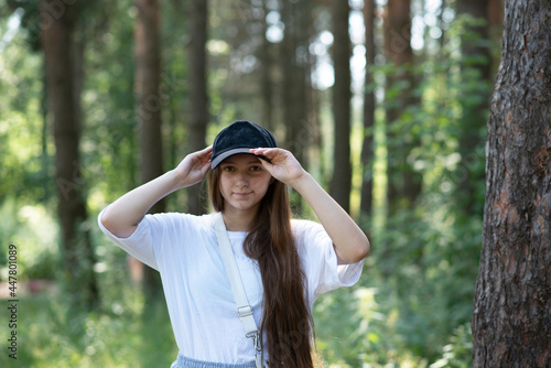portrait of a beautiful teenage girl in the forest. in a white T-shirt and a blue cap