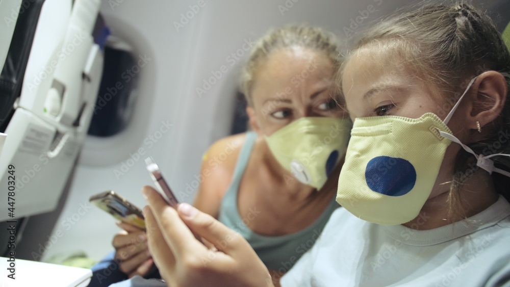Family woman and child baby travel tourist caucasian at plane aircraft with wearing protective medical mask. Read shock news about coronovirus at smartphone mobile. Virus epidemic sars-cov-2 covid-19. Family woman and child baby travel tourist caucasian at plane aircraft with wearing protective medical mask. Read shock news about coronovirus at smartphone mobile. Virus epidemic sars-cov-2 covid-19.