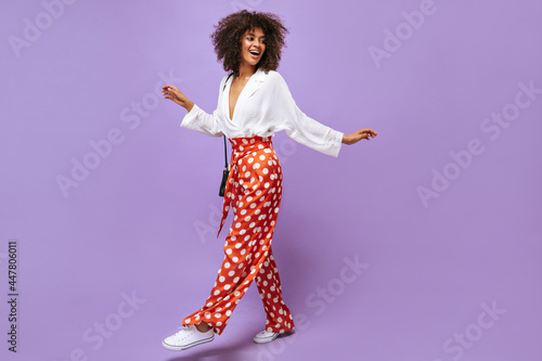Papier peint Stylish lady in wide pants, sneakers and blouse posing on isolated backdrop