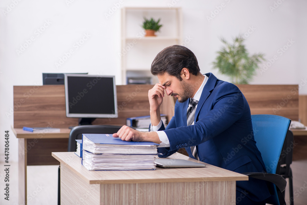 Young male employee and too much work in the office Young male employee and too much work in the office