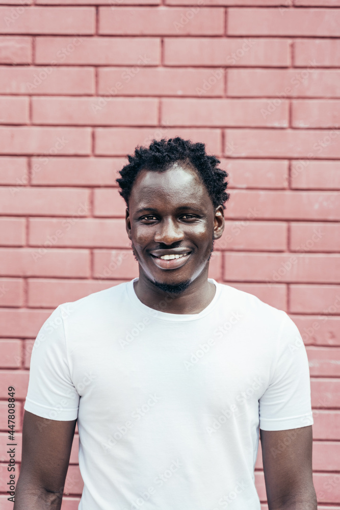Portrait of Handsome smiling young African man over a pink brick wall Portrait of Handsome smiling young African man over a pink brick wall