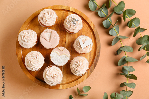 Dessert stand with tasty wedding cupcakes on color background
