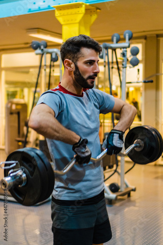 young latino hispanic male lifting a barbell to his chin with weight. vertical photo