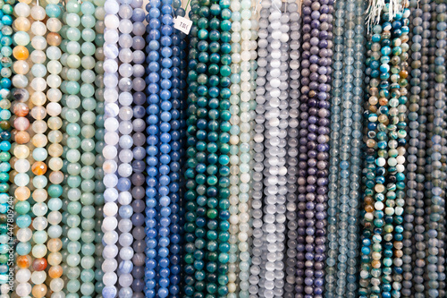 Multicolored beads made of gems strung on thread displayed on stand in store of jewelry accessories