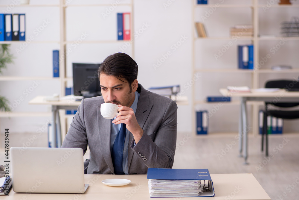 Young male employee drinking coffee during break Young male employee drinking coffee during break