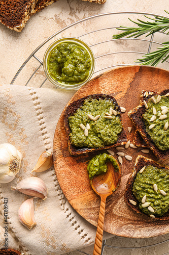 Tasty toasts with pesto sauce on color background