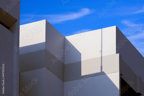 Sunlight and shadow on surface of white building against blue sky background