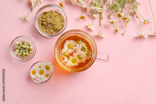 Composition with chamomile tea and dried flowers on color background