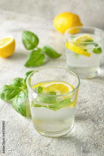 Glasses of tasty lemonade with basil on light background