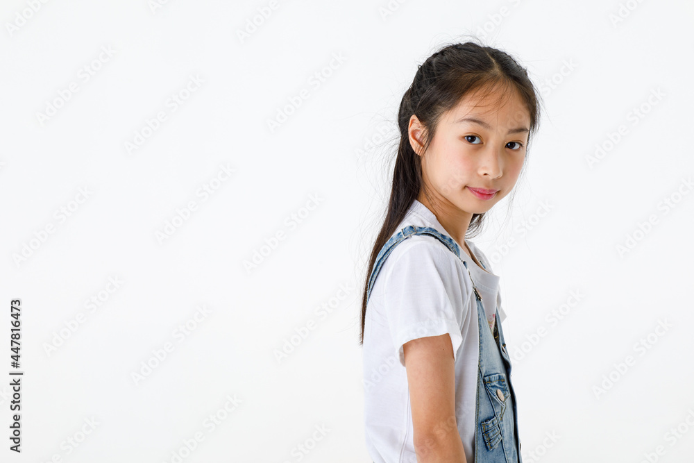Portrait close up isolated studio shot of young pretty cute long black hair elementary girl in jeans denim skirt overalls standing smiling look at camera in front of white background with copy space Portrait close up isolated studio shot of young pretty cute long black hair elementary girl in jeans denim skirt overalls standing smiling look at camera in front of white background with copy space