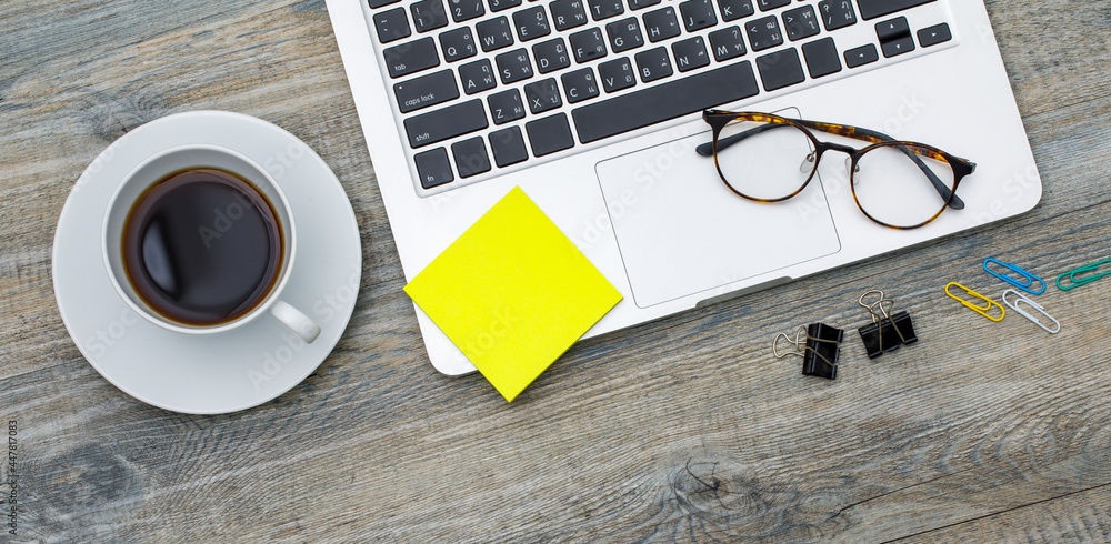 Top view photo of laptop notebook computer and coffee cup and paper note pad on wooden background and copyspace. Business working space concept