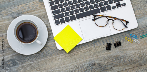 Top view photo of laptop notebook computer and coffee cup and paper note pad on wooden background and copyspace. Business working space concept