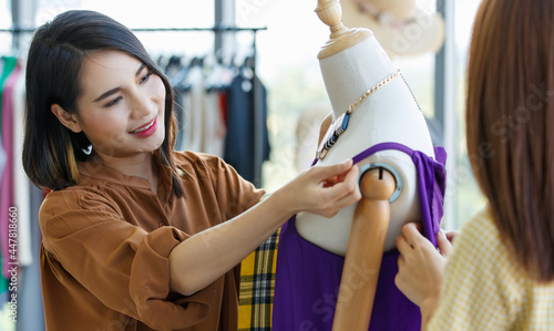 Asian women examining dress on mannequin in shop