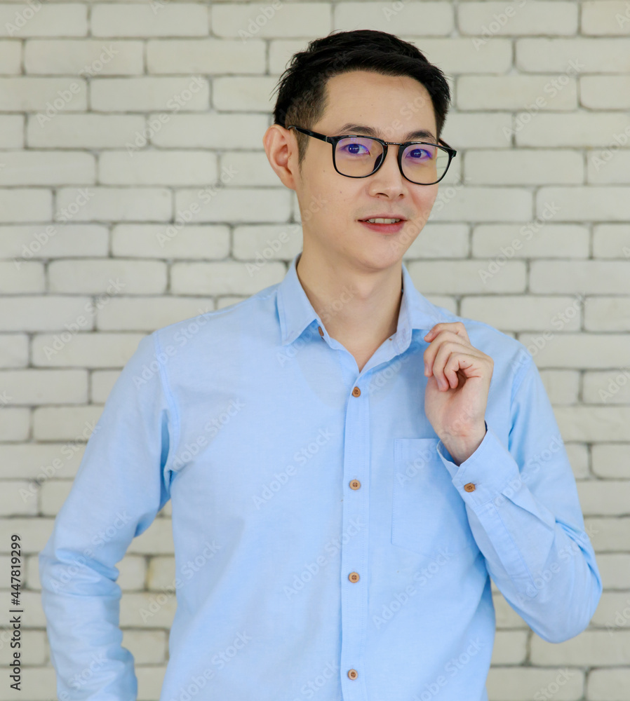 Authentic photo taken with natural light of young and handsome Asian man wearing eyeglasses pose with self-confidence and friendly to camera on brick wall background Authentic photo taken with natural light of young and handsome Asian man wearing eyeglasses pose with self-confidence and friendly to camera on brick wall background