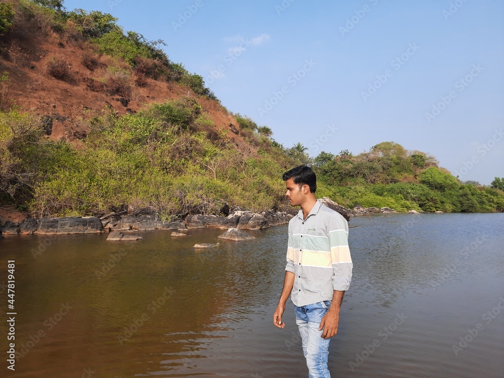 young man standing in the calm water of the lake.  Reflections of the man in the water. beautiful nature view. 