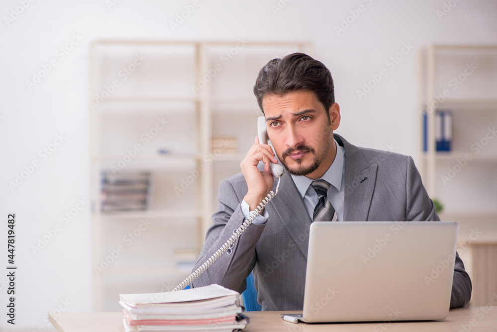 Young male employee unhappy with excessive work in the office Young male employee unhappy with excessive work in the office