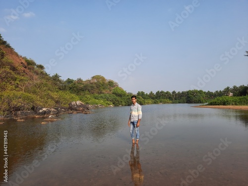 young man standing in the calm water of the lake.  Reflections of the man in the water. beautiful nature view. 