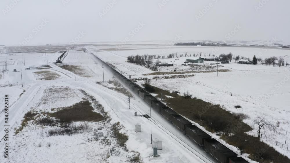 Freight Train Moving On Railway Through Snowy Fields In North Dakota At Winter. aerial panning up Freight Train Moving On Railway Through Snowy Fields In North Dakota At Winter. aerial panning up