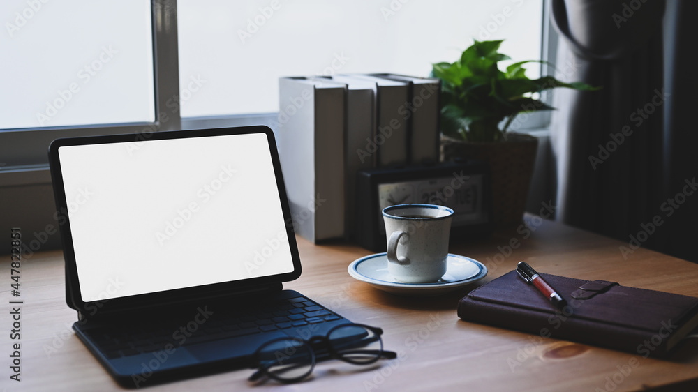 Comfortable workspace with computer tablet, books and coffee cup on wooden desk. Comfortable workspace with computer tablet, books and coffee cup on wooden desk.