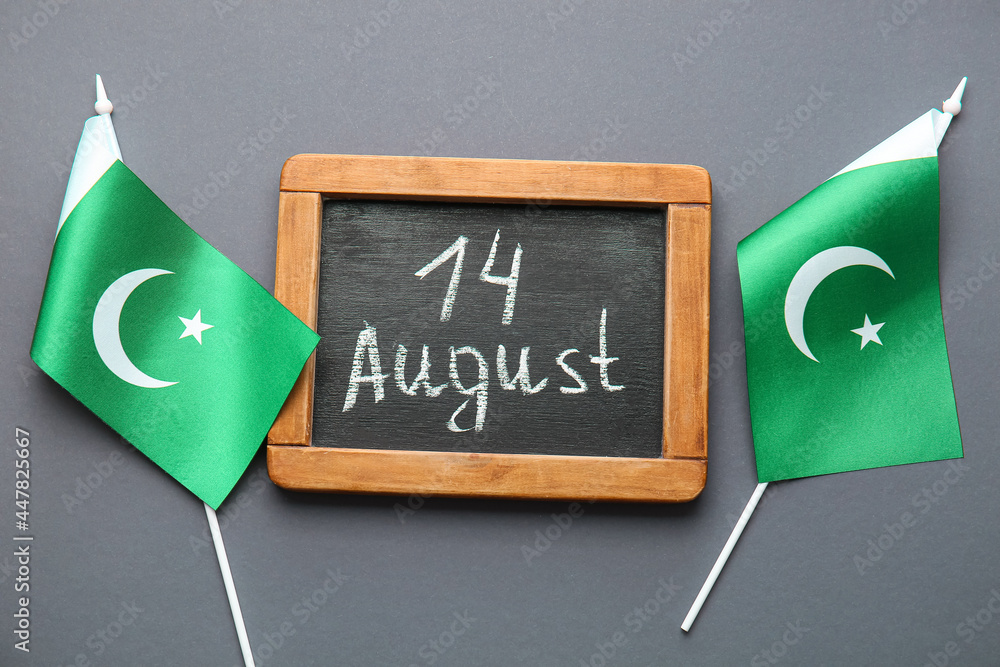 Flags of Pakistan and chalkboard with date of Independence Day on grey background - obrazy, fototapety, plakaty 