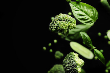 Flying green vegetables on dark background