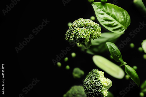 Flying green vegetables on dark background photo