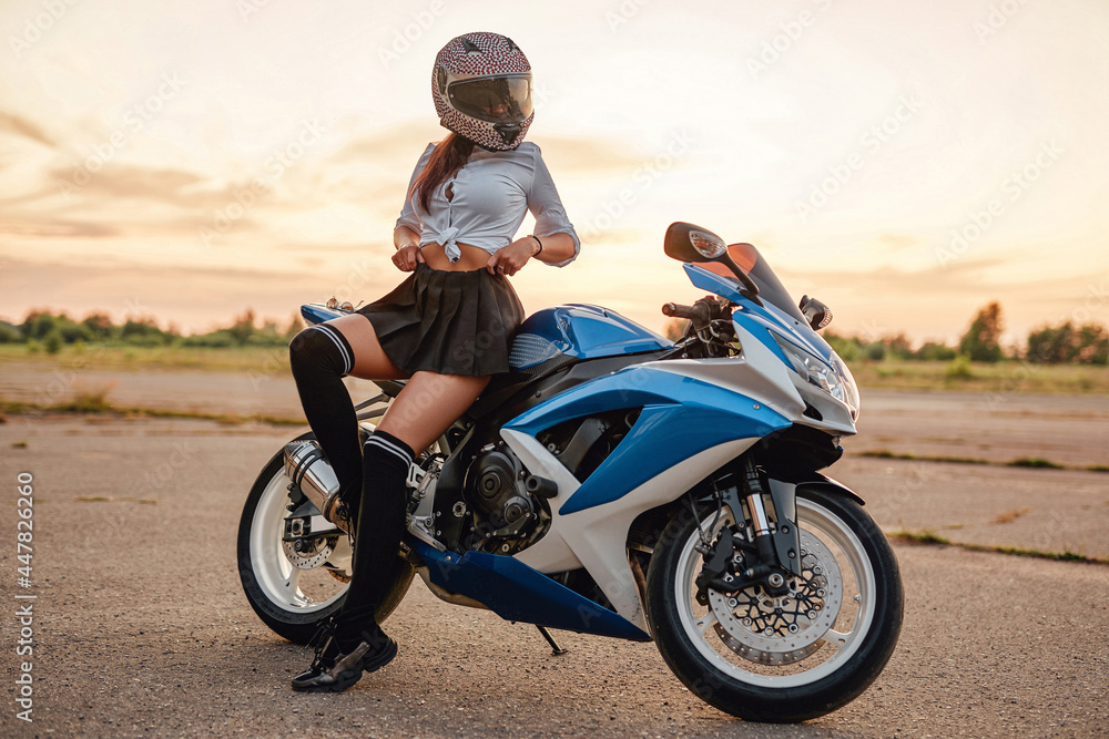 Female motorcyclist and modern motorbike on country road Female motorcyclist and modern motorbike on country road