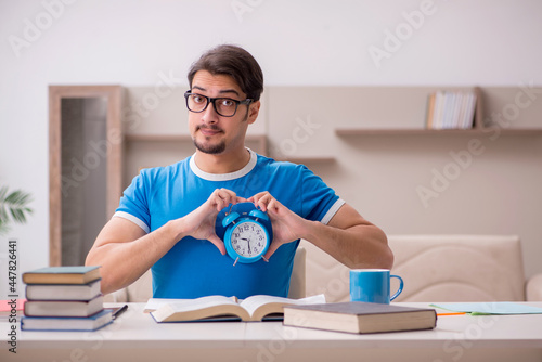 Young male student studying at home in time management concept