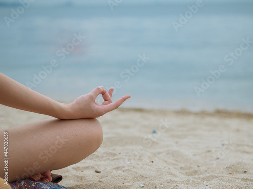 close up photo of hand in lotus posting asana yoga practice on beach