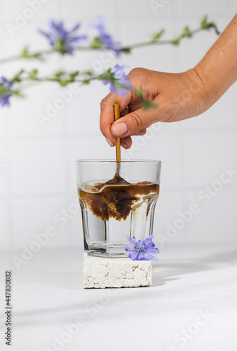 A woman's hand will pour granulated chicory powder into a white mug. Drink chicory.