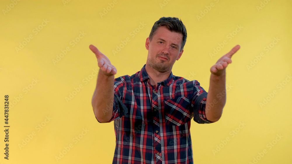 Tall young man deriding somebody, making fun of someone on yellow background. He is in checkered shirt. Tall young man deriding somebody, making fun of someone on yellow background. He is in checkered shirt.