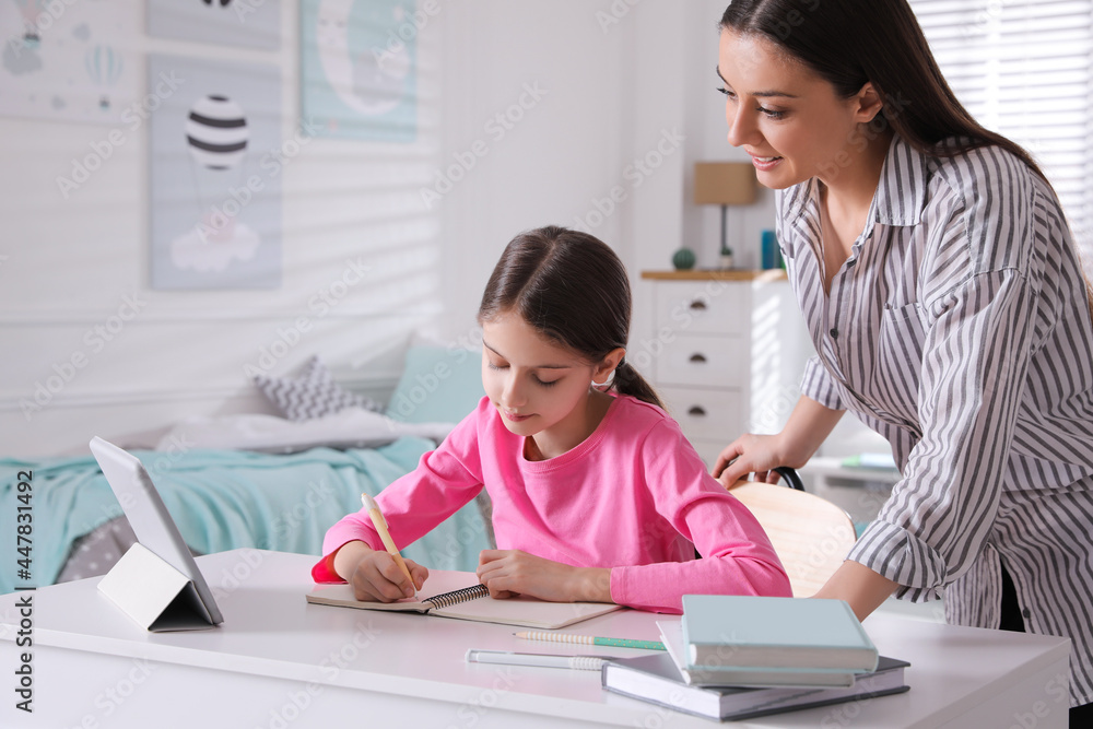 Mother helping her daughter doing homework with tablet at home Mother helping her daughter doing homework with tablet at home